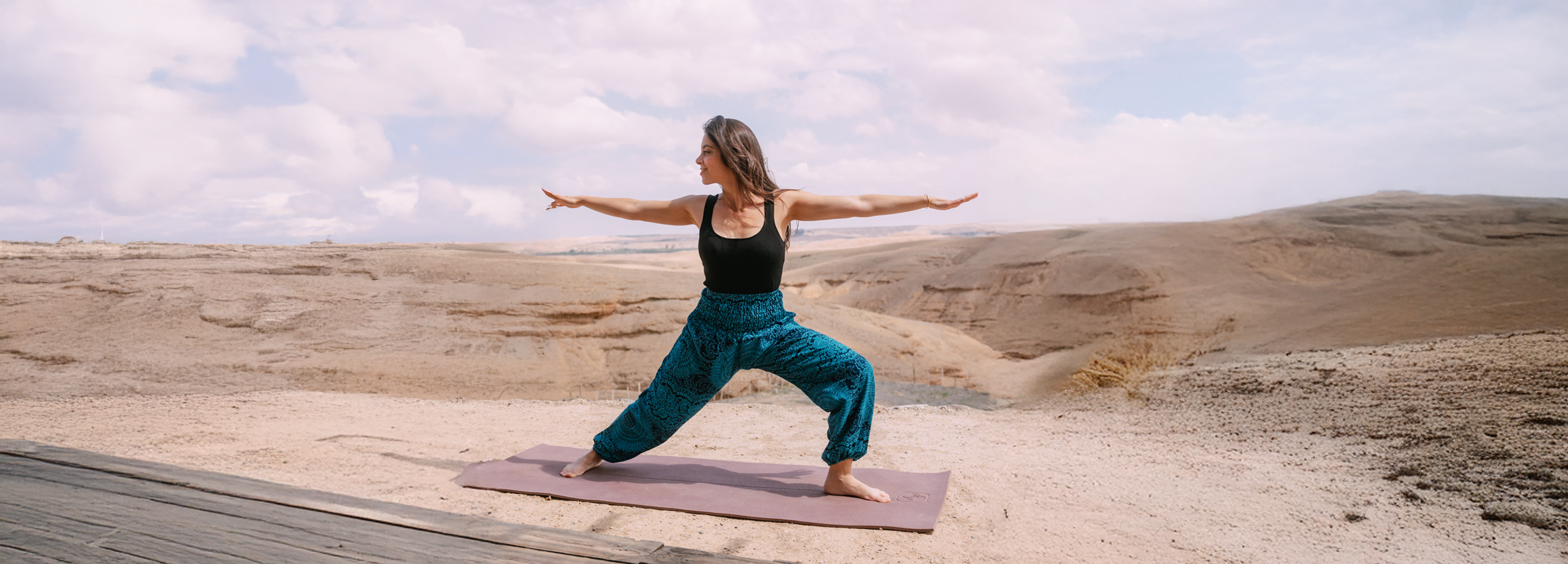 Frau auf einer Yogamatte mitten in der Wüste, macht Übungen und genießt die Weite der Natur.