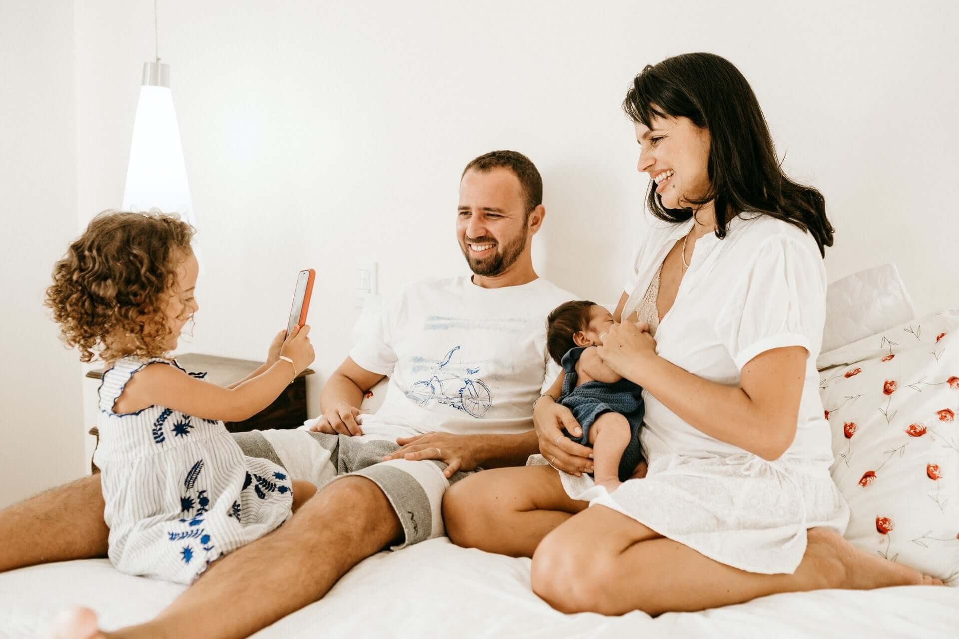 Familie mit zwei Kindern sitzt zusammen auf einem Bett