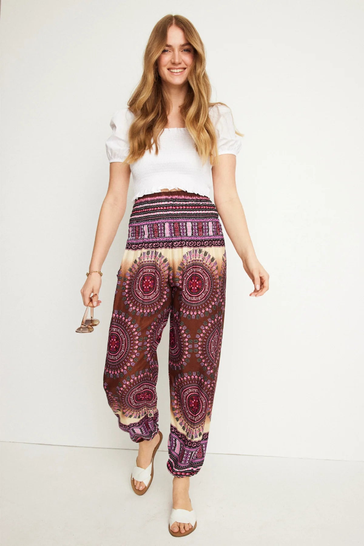 Lachende Frau in der gemusterten Haremshose in Rot- und Violetttönen, kombiniert mit weißem Oberteil