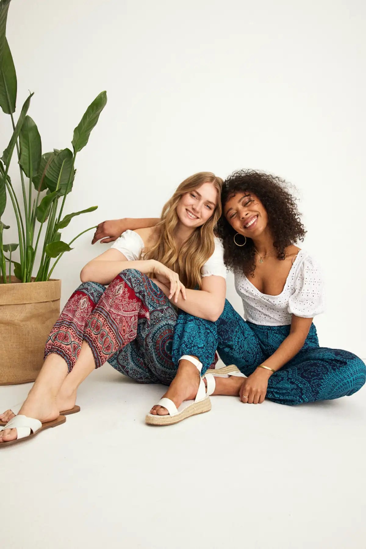 Lachende Frauen eine davon in der gemusterten Haremshose in hellen Rot- und Blautönen, kombiniert mit weißem Oberteil