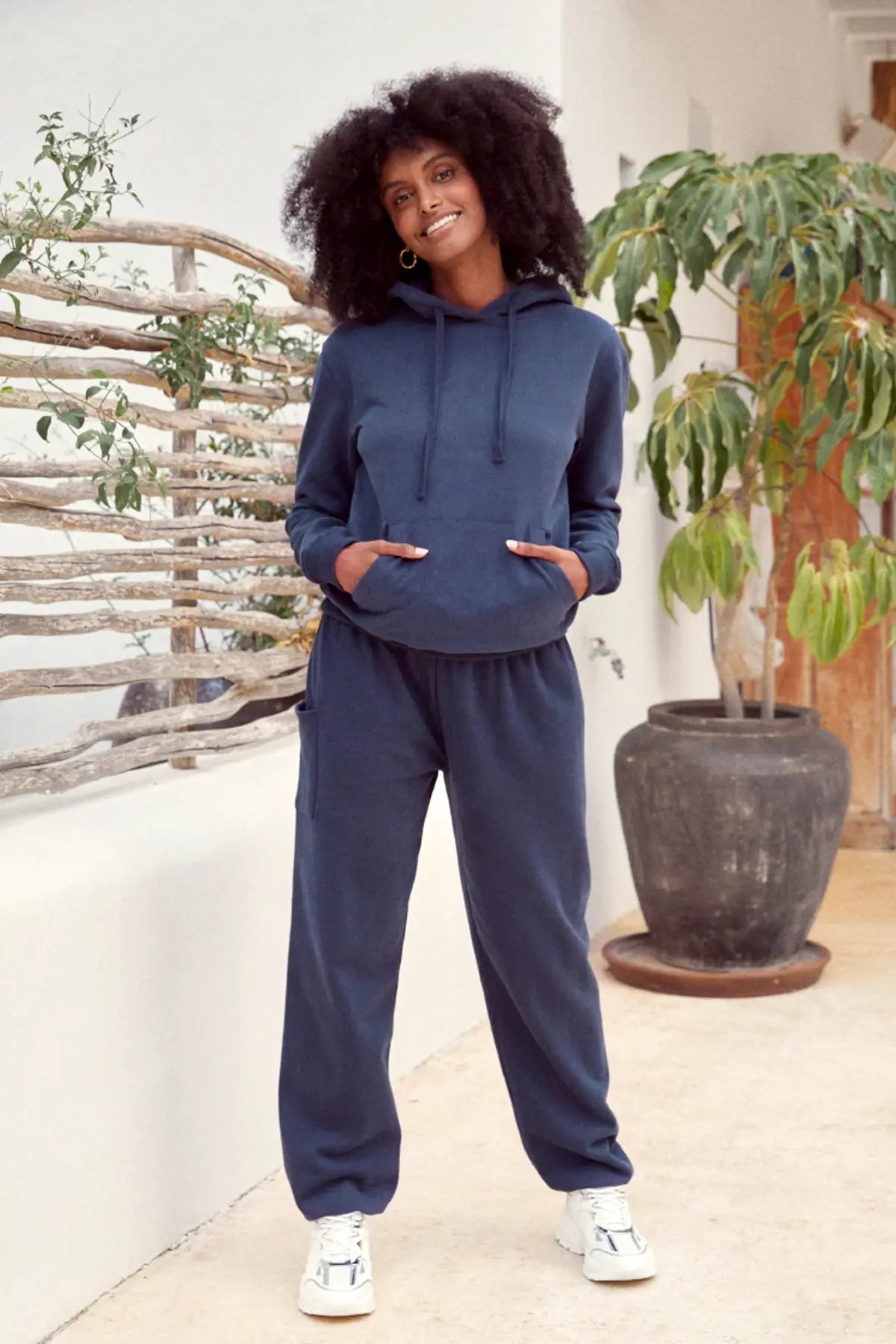 Lachende Frau in warmen Loungewear Haremshose dunkelblau kombiniert mit dem passenden Hoodie in dunkelblau