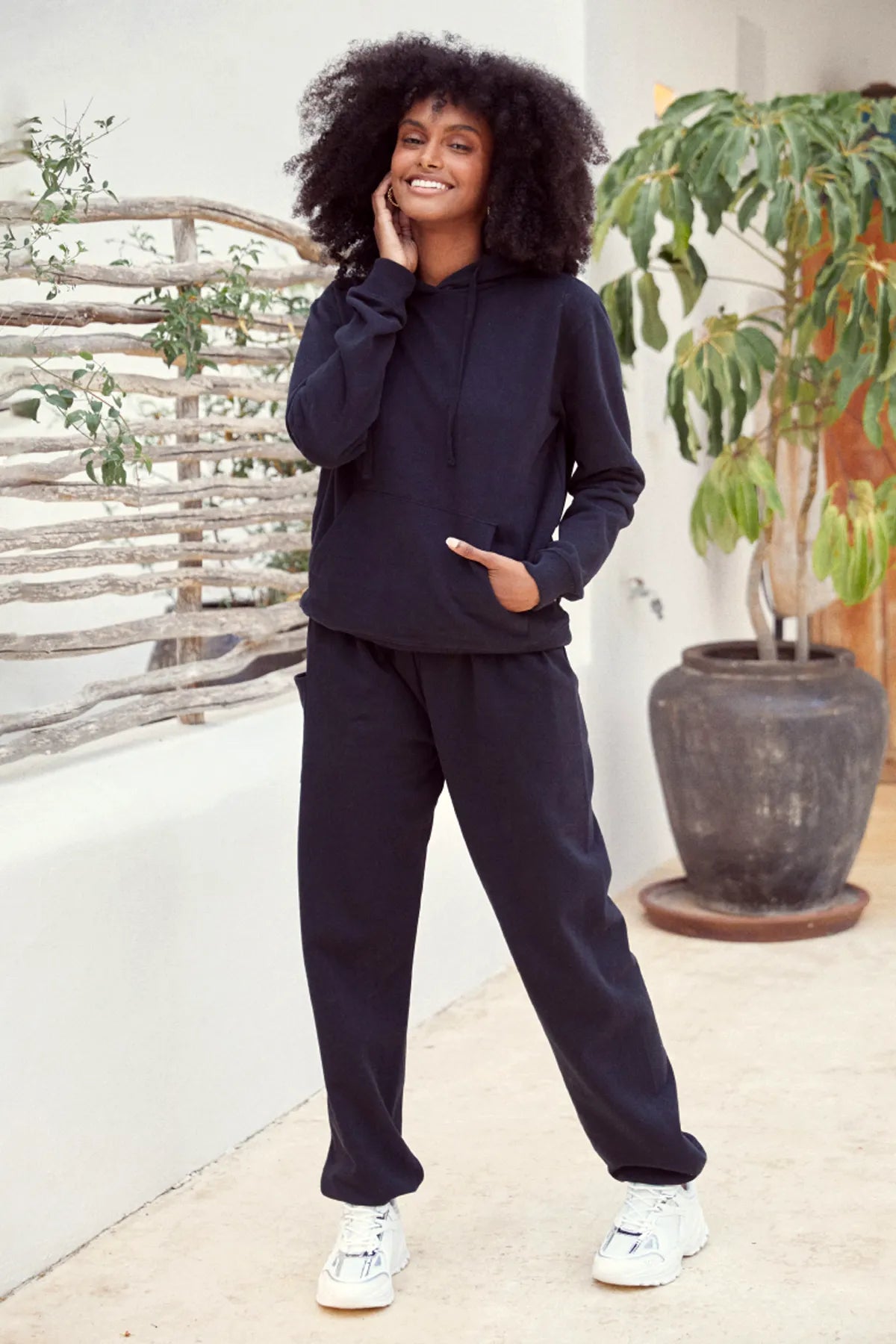 Lächelnde Frau in warmer Loungewear Haremshose Schwarz kombiniert mit schwarzem Hoodie