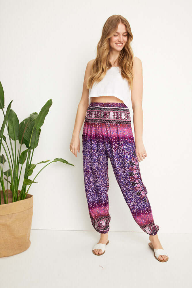 Frontalansicht einer Frau, die die gemusterte Haremshose in violetten Farbtönen trägt