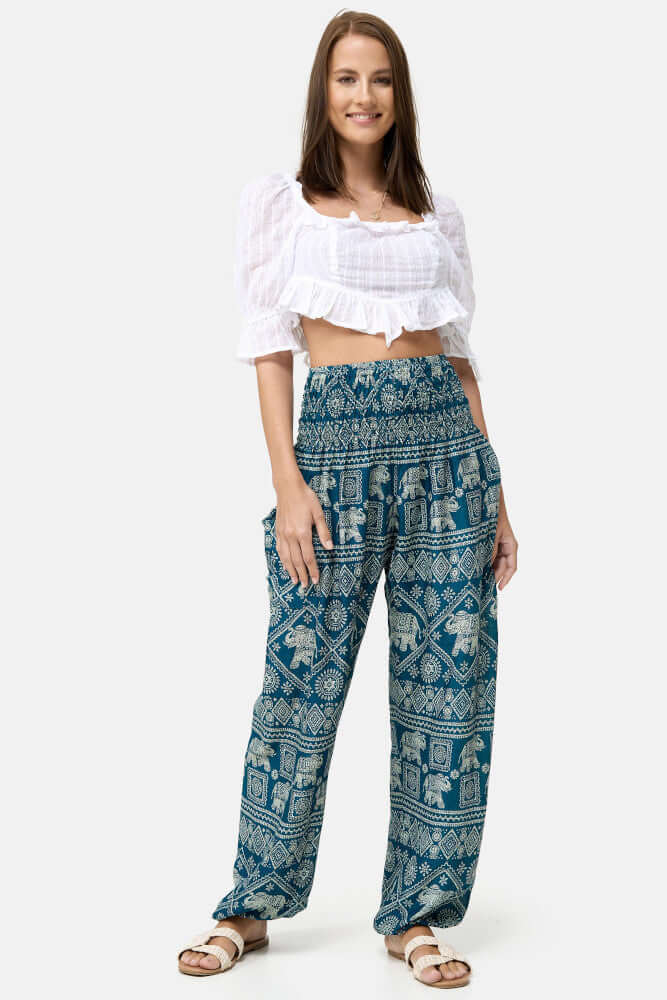 Stehende Frau kombiniert die Türkise Haremshose mit einem weißen Top