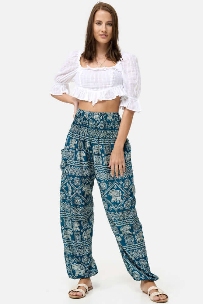 Stehende Frau kombiniert die Türkise Haremshose mit einem weißen Top