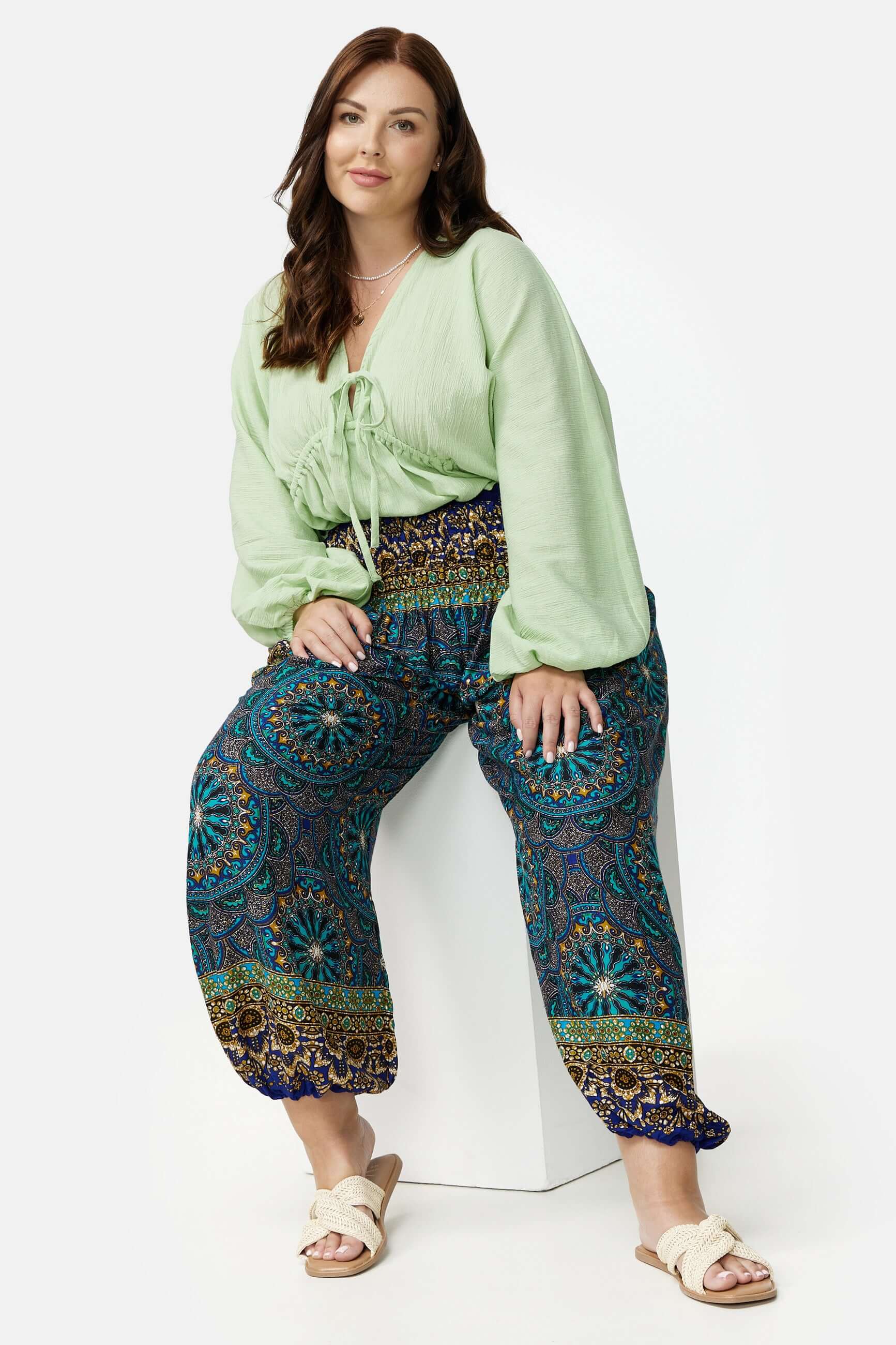Frau in blau gemusterter Haremshose Plus Size sitzend