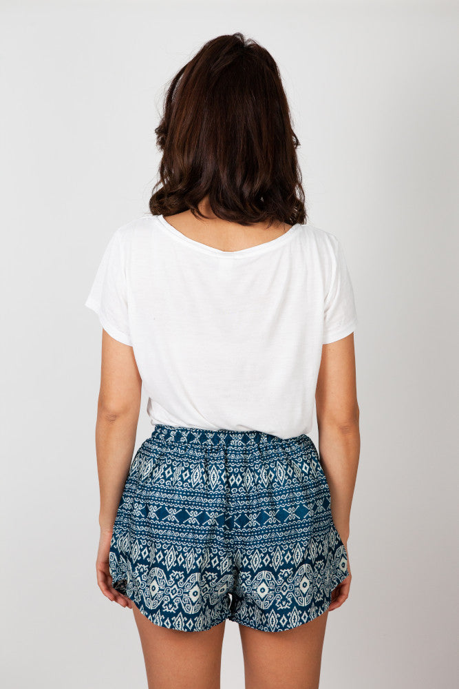 Frau in grün gemusterter Wald Labyrinth Shorts von hinten