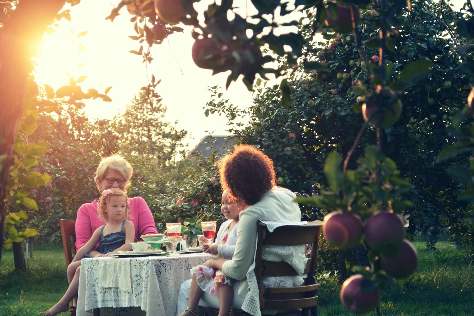 Familie sitzt im Garten zusammen am Tisch beim nachhaltig Essen