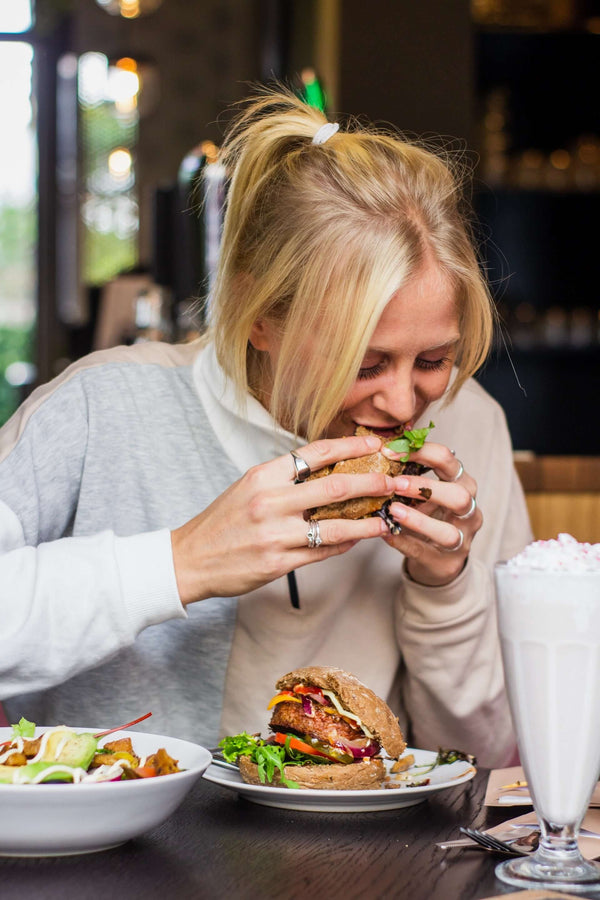 Essen ohne Hunger: Frau beißt in einen Burger