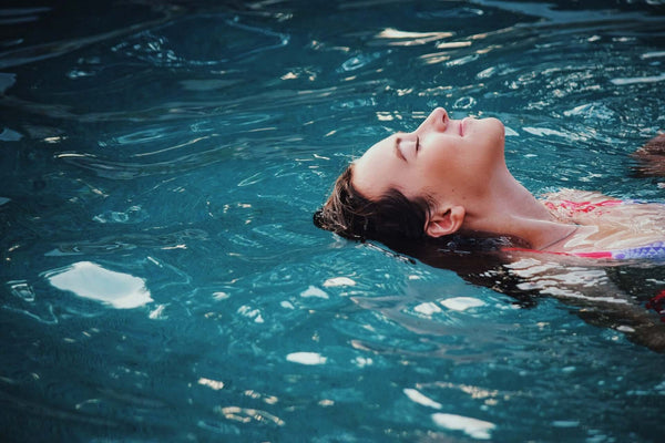 Frau schwimmt im Wasser mit geschlossenen Augen