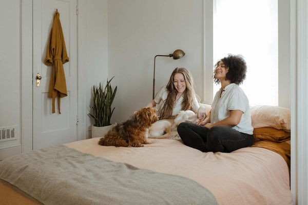 zwei Menschen sitzen mit einem Hund auf dem Bett und führen tiefe Gespräche