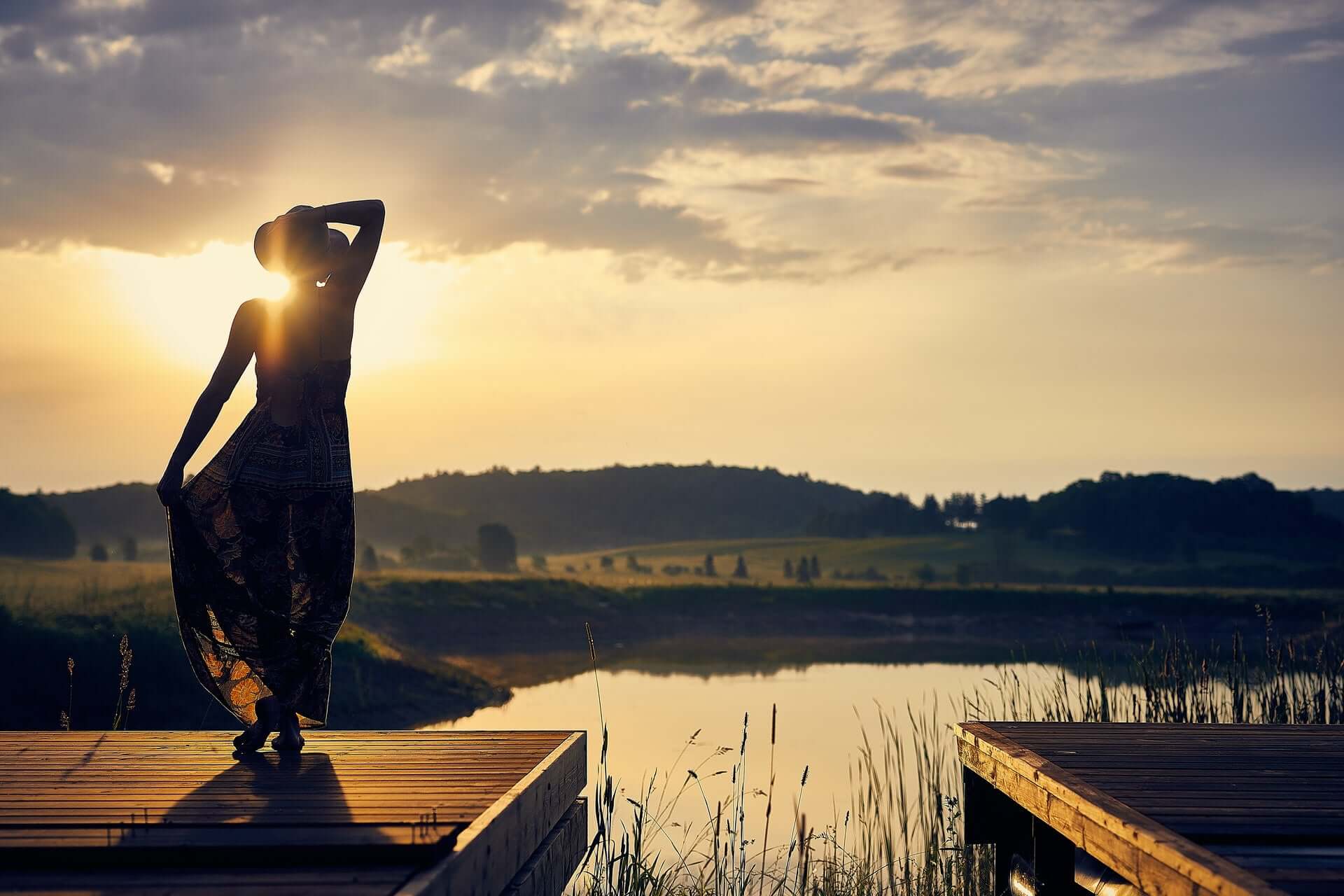 Person steht bei Sonnenschein am Ufer eines Sees und schaut in die Ferne