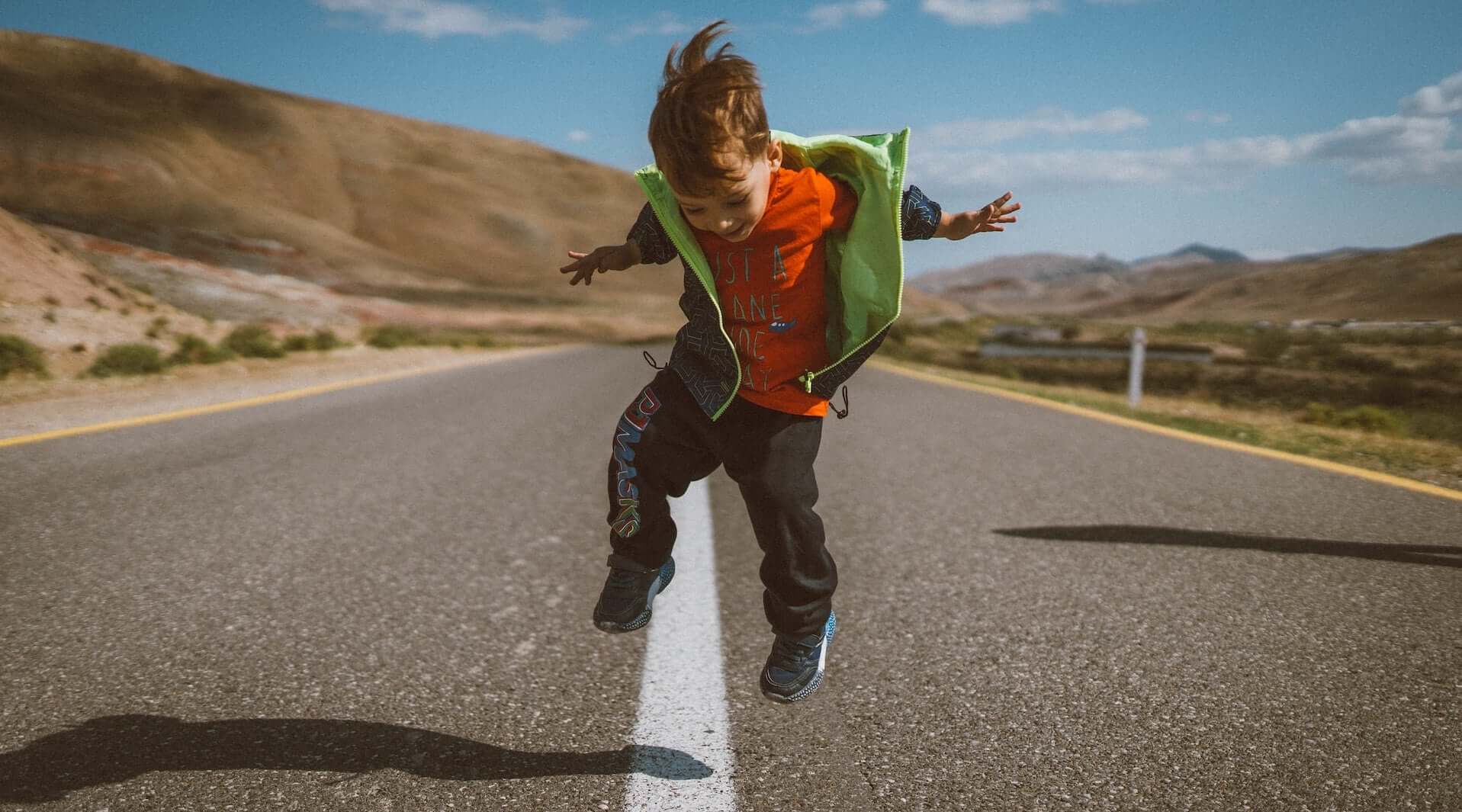 Kind springt freudig auf einer Straße