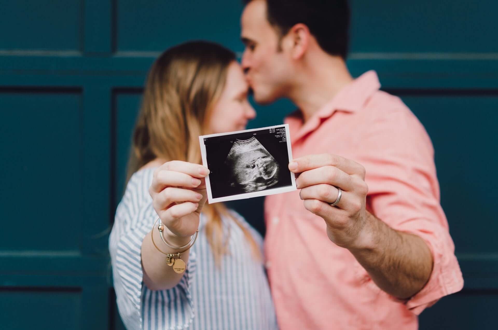 Vater und Mutter halten Ultraschallbild in den Händen