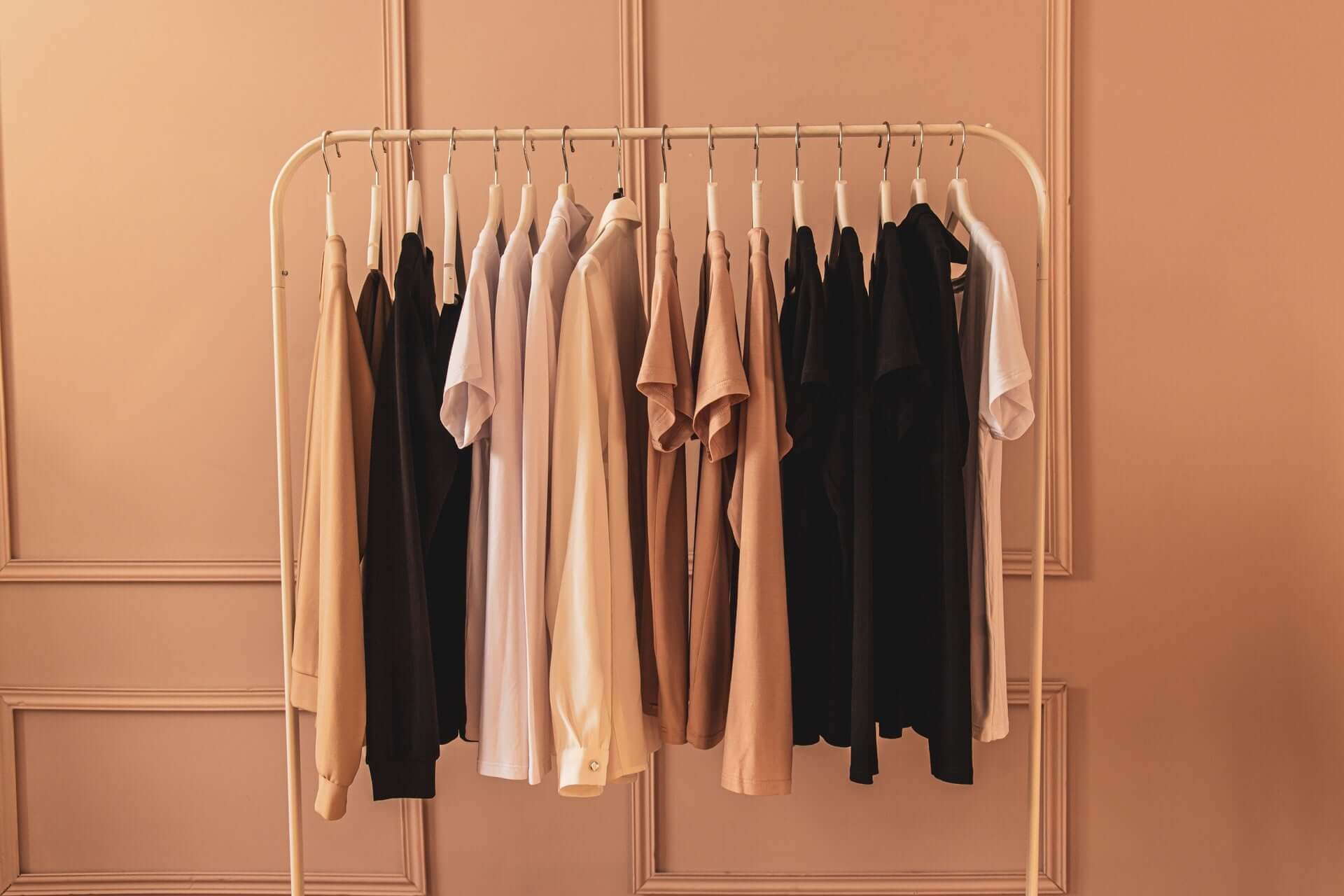 Capsule Wardrobe Beispiel: Basic Garderobe in gedeckten Farben an einem Kleiderständer