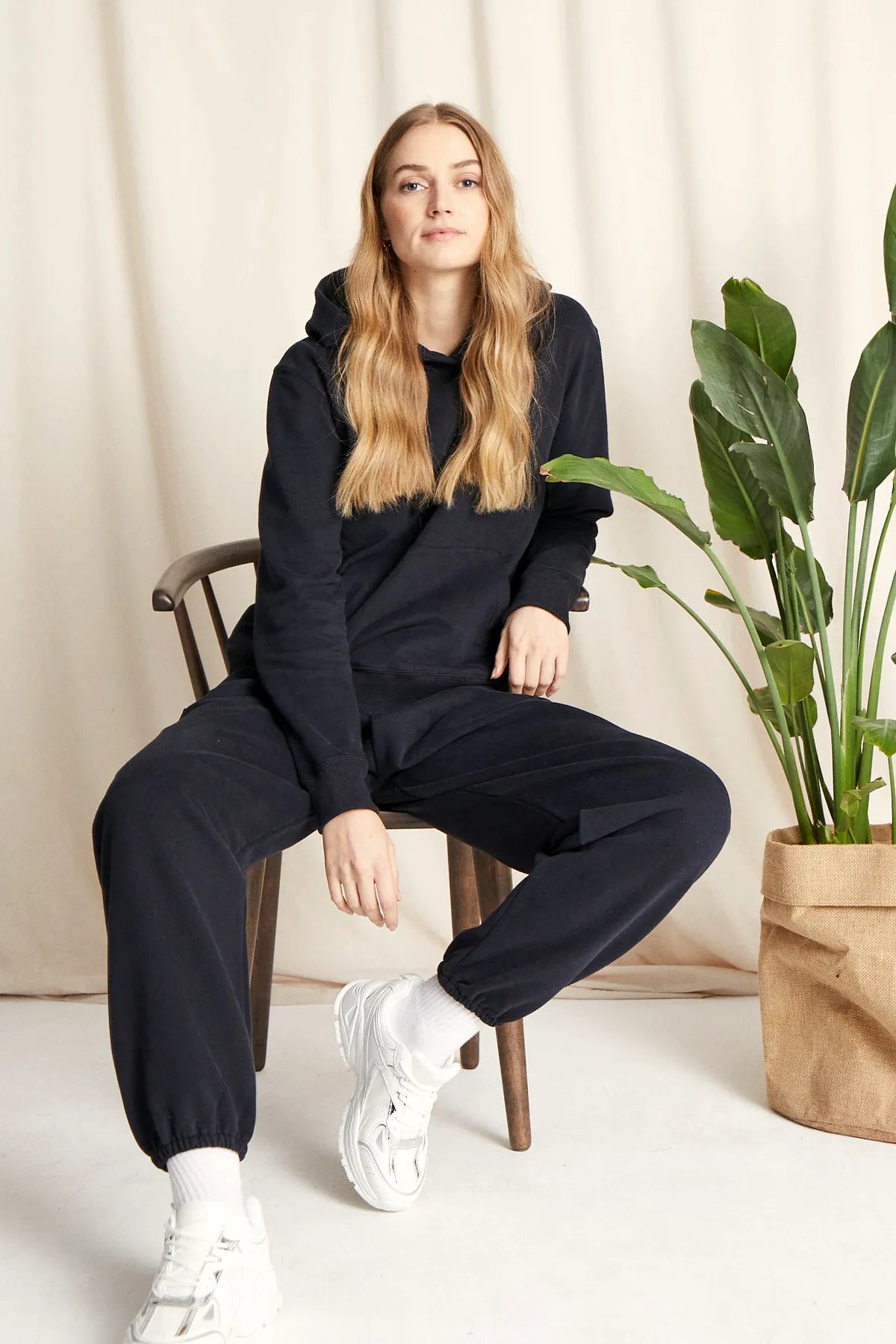 Sitzende Frau in warmer Loungewear Haremshose Schwarz kombiniert mit schwarzem Hoodie