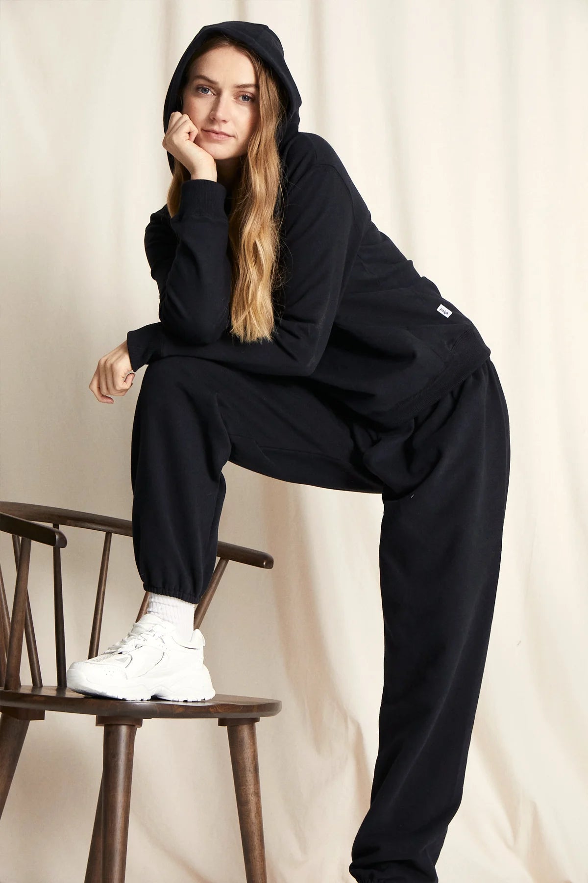 Stehende Frau in warmer Loungewear Haremshose Schwarz kombiniert mit schwarzem Hoodie