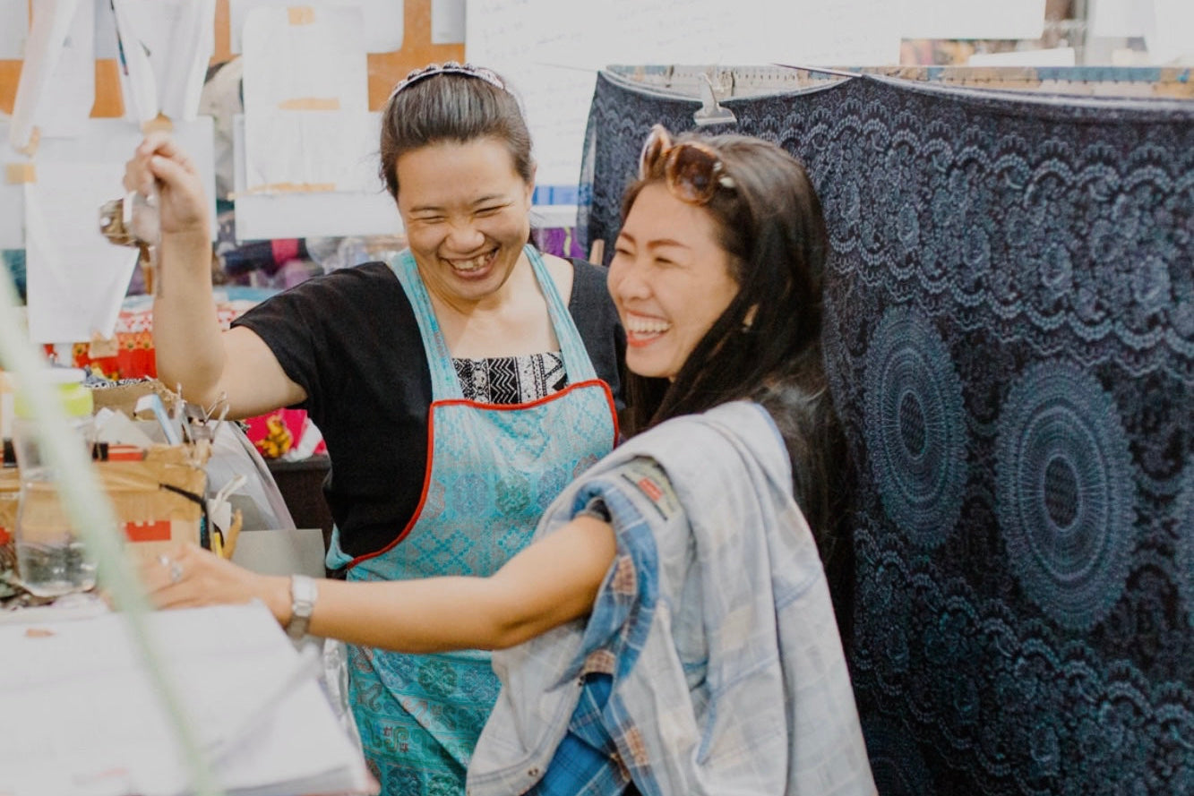 Zwei lachende Frauen stehen in einer paigh-Produktionsstätte