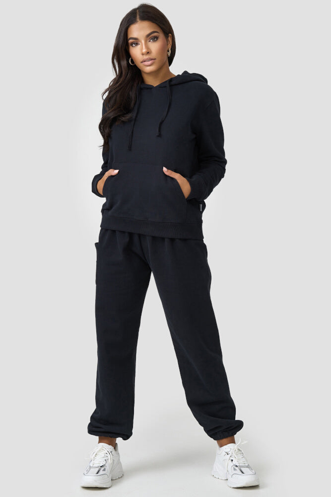 Stehende Frau in warmer Loungewear Haremshose Schwarz kombiniert mit schwarzem Hoodie