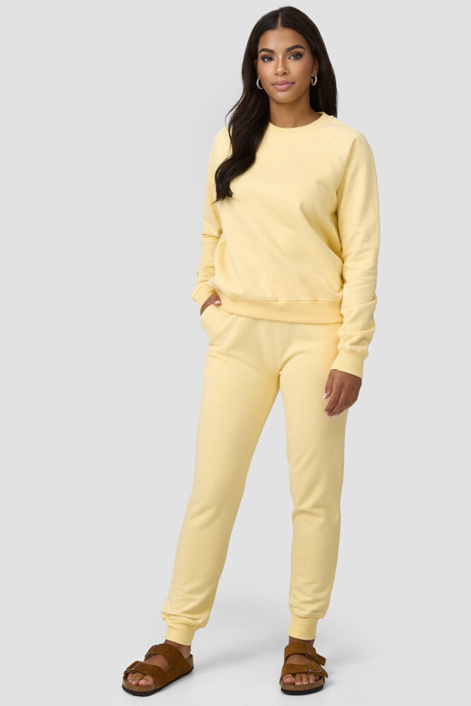 Frau kombiniert den gelbfarbigen Sweater mit einer gleichfarbigen Sweatpants