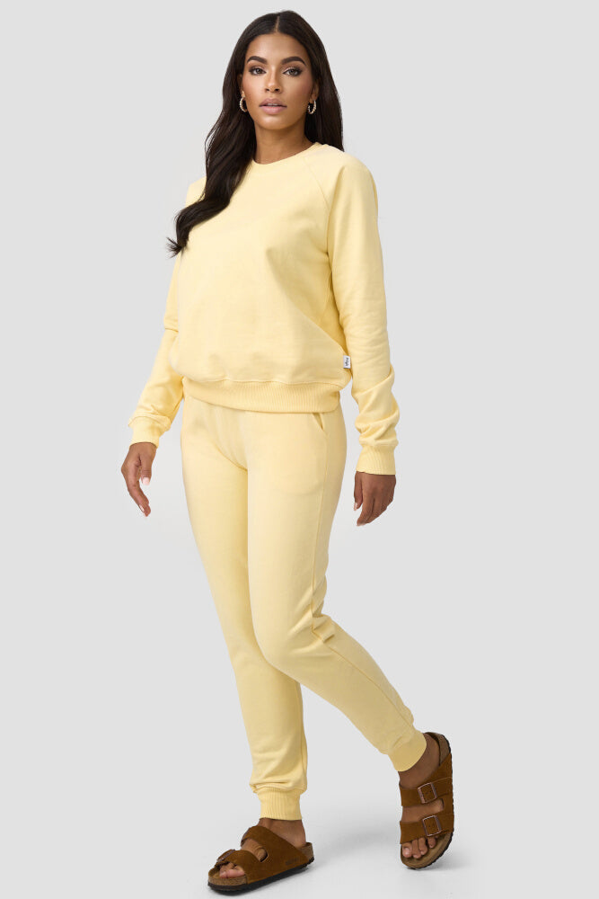 Frau kombiniert den gelbfarbigen Sweater mit einer gleichfarbigen Sweatpants