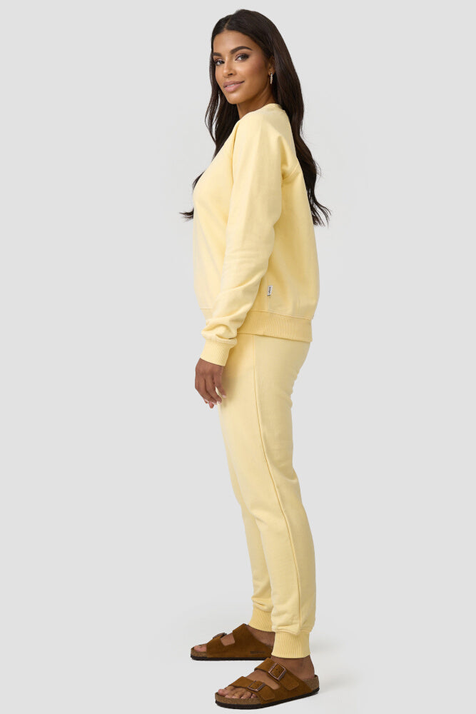 Seitenansicht der Frau, die den gelbfarbigen Sweater mit einer gleichfarbigen Sweatpants kombiniert