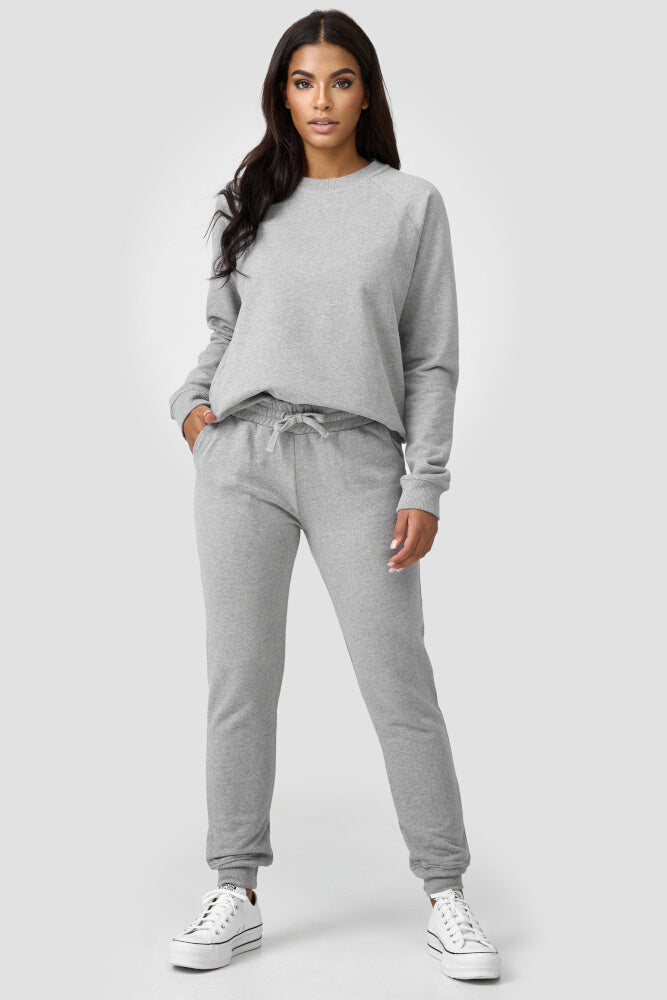 Frau kombiniert den graufarbigen Sweater mit einer graufarbigen Sweatpants
